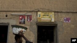 A vendor walks past a shop decorated with election posters supporting presidential candidate Dramane Dembele, in the central market area of Timbuktu, Mali, July 22, 2013.