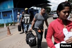Venezuelans walk to show their passports or identity cards at the Pacaraima border control, Roraima state, Brazil, Nov. 16, 2017. The border control is manned by Federal Police only during the day.