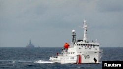A Chinese Coast Guard vessel, with the disputed oil rig in the background, is seen in the South China Sea June 13, 2014.