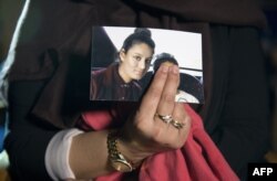 FILE - A picture of Shamima Begum is held by her sister, who was being interviewed by reporters in central London, Feb. 22, 2015. Britain last week revoked nationality of Shamima Begum, a 19-year-old woman of Bangladeshi heritage who joined IS in Syria in 2015. Her fate in a refugee camp in eastern Syria remains uncertain.