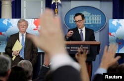 FILE - U.S. Treasury Secretary Steven Mnuchin, right, and White House National Security Adviser John Bolton announce economic sanctions against Venezuela and the Venezuelan state-owned oil company Petroleos de Venezuela (PdVSA) during a press briefing at the White House, Jan. 28, 2019.