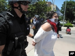 Police officers take a woman into custody after a campaign rally for Republican presidential candidate Donald Trump in Fresno, Calif., May 27, 2016.