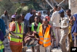 Somalis carry away the body of a civilian victim who was shot dead by gunmen during a suicide car bomb attack on a government building in Mogadishu, Somalia, March 23, 2019.