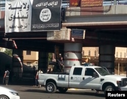 FILE - A fighter from the Islamic State, formerly known as the Islamic State of Iraq and the Levant (ISIL), mans an anti-aircraft gun mounted on the rear of a vehicle in Mosul, Iraq, July 16, 2014.