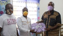Remise des masques en tissu entre le SGA de BATIR, Fiacre Atsu (en blanc) et le directeur du collège Jean-Baptiste, Théophile Dika (en chemise imprimé wax), Lomé, le 4 juin 2020. (VOA/Kayi Lawson)