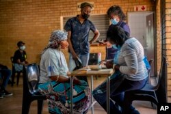 FILE - People are processed before receiving their shot against COVID-19 Friday Dec. 3, 2021 at the Orange Farm, South Africa, multipurpose center. (AP Photo/Jerome Delay)