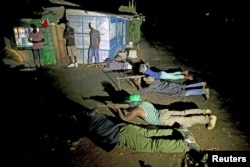 FILE - Armed vigilantes lay on the ground with their rifles as they patrol in the center of Bujumbura, Burundi, Nov. 20, 2015.