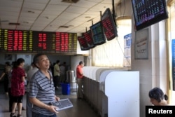 An investor looks at electronic boards showing stock information at a brokerage house in Shanghai, China, Sept. 1, 2015.