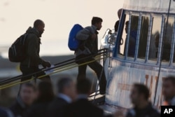 Migrants get on a ferry at the port of Mytilini in the Greek island of Lesbos, Monday, April 3, 2016.