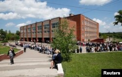 People stand in a line to enter a polling station and to take part in the referendum on the status of Donetsk, eastern Ukraine, May 11, 2014.