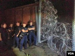 Hungarian soldiers seal a gap in a fence by using a single car train wrapped in barbed wire, Hungary border, Sept. 14, 2015. (A. Tanzeem/VOA)