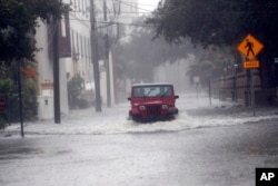 A motorist drives down flooded street in St. Augustine, Fla., as Hurricane Matthew moves up the Florida coast Oct. 7, 2016.