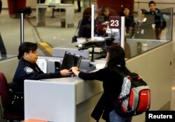 A foreign airline passenger hands travel documents to a Customs and Border Protection officer at Hatsfield-Jackson International Airport in Atlanta, Jan. 5, 2004.