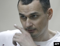 FILE - Ukrainian film director Oleg Sentsov looks out from a defendants' cage as he listens to the verdict at a military court in the southern city of Rostov-on-Don, Aug. 25, 2015.