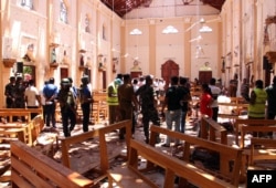 Sri Lankan security personnel walk through debris following an explosion in St Sebastian's Church in Negombo, north of the capital Colombo, on April 21, 2019.