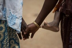 Pengungsi Nigeria berusia lima belas tahun, Fati, berjalan bersama ibunya, Mariam, sambil menggendong adiknya di kamp pengungsi Minawao, Kamerun Utara, 5 April 2016. (Karel Prinsloo/UNICEF/Handout via REUTERS)