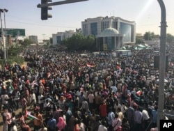 Sudanese demonstrators march with national flags as they gather during a rally demanding a civilian body to lead the transition to democracy, outside the army headquarters in the Sudanese capital Khartoum, April 13, 2019.
