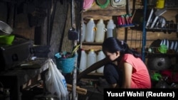 Seorang gadis yang menikah di bawah umur pada Maret 2020, sedang memasak di dapur rumahnya di Botteng Utara di Mamuju, Sulawesi Barat, pada 24 Juli 2020. (Foto: AFP/Yusuf Wahil)
