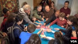 People of all ages are dismantling the sand mandala that is an integral part of the ancient ritual art. (VOA/ J. Soh)