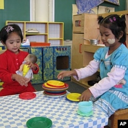 Girls play dinner-time with a doll