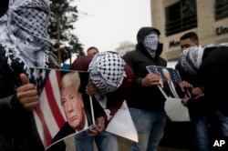 Palestinians holds posters of the U.S. President Donald Trump during a protest in the West Bank City of Ramallah, Dec. 6, 2017.