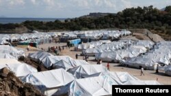 FILE - Refugees and migrants make their way in the Kara Tepe camp on the island of Lesbos
