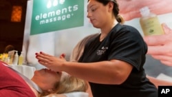FILE - Adrianna DeJesus, right, of Elements Massage in Englewood, Colo., demonstrates their AromaRitual experience at the annual International Spa Association event, in New York, Tuesday, Aug. 7, 2018. (AP Photo/Richard Drew)