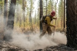 Firefighter Garrett Suza, with the Chiloquin Forest Service, mops up a hot spot on the North East side of the Bootleg Fire, July 14, 2021, near Sprague River, Ore.