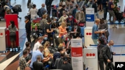 People line up to get on an Air France flight to Paris at O.R. Tambo International Airport in Johannesburg, South Africa, Nov. 26, 2021. Several nations have moved to stop air travel from southern Africa in reaction to discovery of a new COVID-19 variant in South Africa.