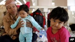 A girl sits with her mother and brother while resting in a mosque in the northern Macedonian city of Kumanovo, June 22, 2015. 