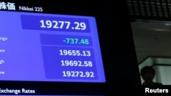 A man is seen behind an electronic board showing the Nikkei average after the New Year's opening ceremony at the Tokyo Stock Exchange, held to wish for the success of Japan's stock market, in Tokyo, Jan. 4, 2019. 