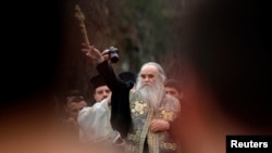 Arhiva - Mitropolit Amfilohije Radović, među vjernicima, baca drveni krst u rijeku Ribnicu tokom proslave Bogojavljanja, u Podgorici, 19. januara 2013. (Rojters)