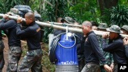 Soldiers carry a pump to help drain the rising floodwater in a cave where 12 boys and their soccer coach have been trapped since June 23, in Mae Sai, Chiang Rai province, in northern Thailand, July 6, 2018. 