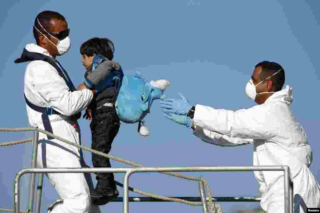 Armed Forces of Malta (AFM) sailors disembark a would-be immigrant child from an AFM offshore patrol vessel at the AFM Maritime Squadron base at Haywharf in Valletta's Marsamxett Harbour, Malta. 41 immigrants, claiming to be Syrians and Palestinians, were rescued from a boat in distress 89 nautical miles south of Malta in a joint operation between Maltese and Italian forces, according to army sources.