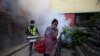 A Nepalese woman covers her face as a worker fumigates an area in an attempt to control mosquito-borne diseases in Kathmandu, Nepal, Sept. 5, 2019. The government says dengue cases has shot up by more than 65% across the country in the last week.