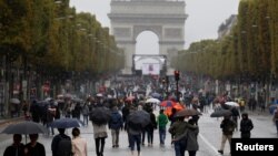 FILE - Pedestrians walk on the Champs Elysees avenue during the Car Free Day in Paris, Oct. 1, 2017. 