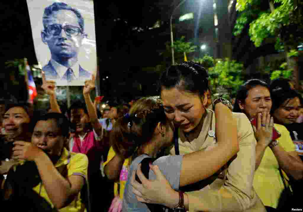 Warga yang berduka cita menangis dan berpelukan di luar rumah sakit Siriraj, Bangkok, tempat Raja Thailand dirawat (13/10). (Reuters/Jorge Silva)