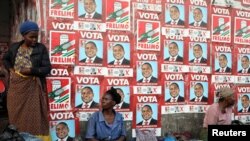 Women, selling charcoal, chat in front of the ruling FRELIMO party election posters in the capital, Maputo, Mozambique August 31, 2019. REUTERS/Siphiwe Sibeko