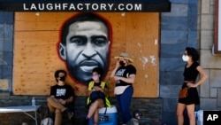 洛杉矶抗议者站在街边一副巨大的弗洛伊德壁画前面。