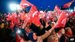 People wave Turkish flags as they listen to Turkey's President Recep Tayyip Erdogan during a rally to honor the victims of the July 15, 2016 failed coup attempt, part of the ceremonies for the three-year anniversary, in Istanbul, July 15, 2019.