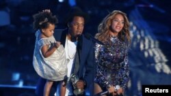FILE - Jay-Z presents the Video Vanguard Award to his wife, Beyonce, as he holds their daughter, Blue Ivy, during the 2014 MTV Video Music Awards in Inglewood, California, Aug. 24, 2014.