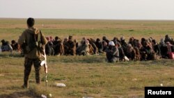 Seorang tentara Pasukan Demoktratik Suriah (SDF) yang didukung AS, berjaga dekat warga sipil dekat Desa Baghouz, Provinsi Deir Al Zor, Suriah, 22 Februari 2019. 