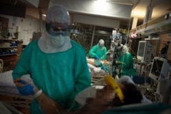 FILE - Health care workers attend to COVID-19 coronavirus patients at the Intensive Unit Care of the Povisa Hospital in Vigo, northwestern Spain, April 16, 2020.