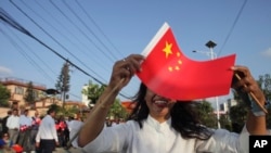 A woman holds a Chinese flag and stands by the side of a road to welcome Chinese President Xi Jinping in Kathmandu, Nepal, Oct. 12, 2019. 
