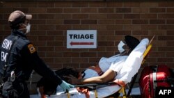 FILE - A medical worker transports a patient outside a special COVID-19 area at Maimonides Medical Center, in the Brooklyn borough of New York City, May 17, 2020.