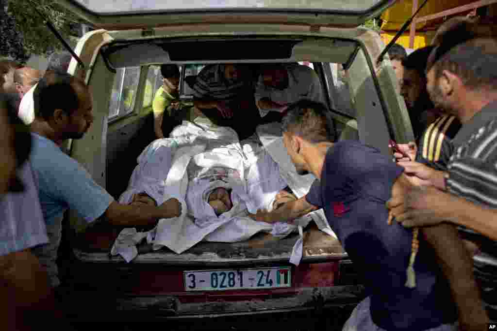 Relatives take the bodies of four Palestinians, who relatives say were killed in a missile strike, from the hospital for burial, in Beit Lahiya, Gaza Strip, Aug. 4, 2014.
