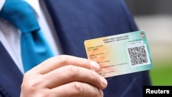 Hungary's Prime Minister Viktor Orban shows a Hungarian immunisation certificate against the coronavirus disease (COVID-19) as he answers the media questions, following the meeting with Britain's Prime Minister Boris Johnson, at Downing Street in London, 