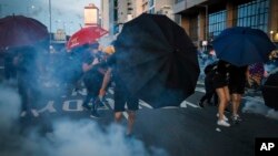 Učesnici protesta u Hong Kongu "brane" se kišobranima od suzavca, 28. jul 2019.