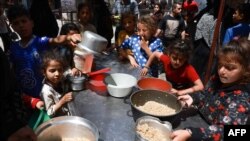 FILE - Displaced Palestinian children line up to receive food in Rafah, on the southern Gaza Strip on April 19, 2024, amid ongoing battles between Israel and Hamas. 