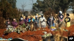 Mourners pray during a burial ceremony at the Olifantsveil Cemetery outside Johannesburg, South Africa, Aug. 6, 2020. The frequency of burials in South Africa has significantly increased during the coronavirus pandemic.